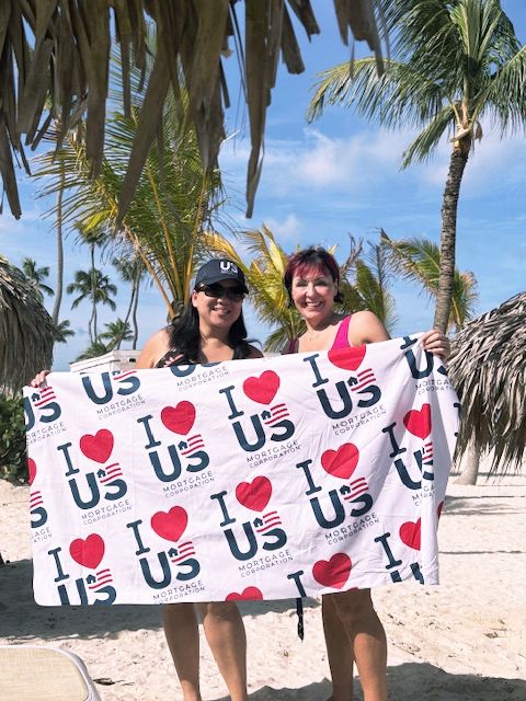 US Mortgage colleagues holding an I Love US banner on the beach